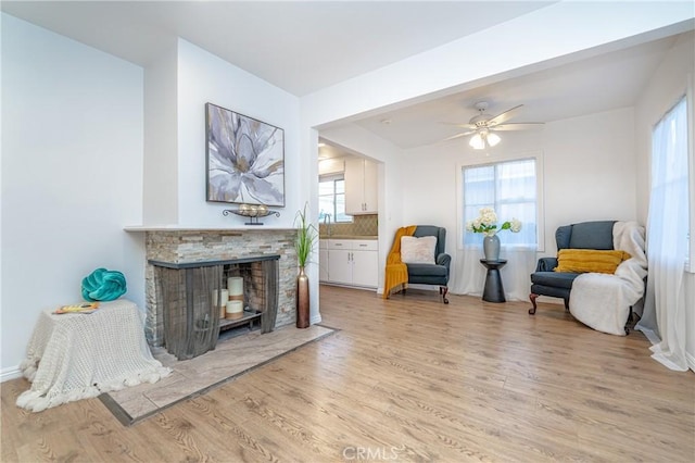 sitting room featuring a fireplace, light wood-type flooring, and ceiling fan