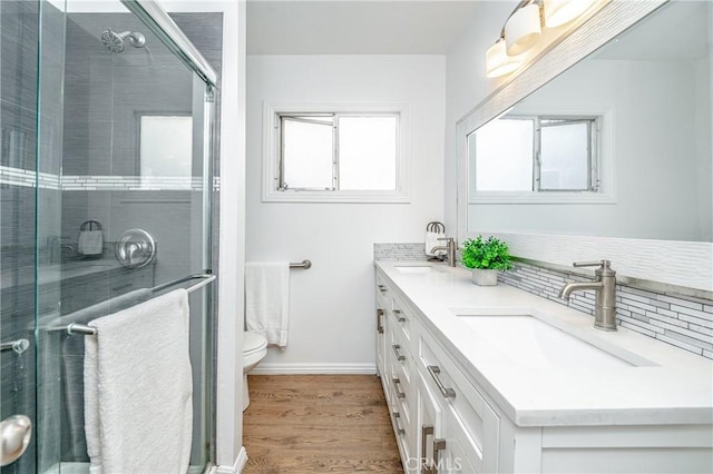 bathroom featuring decorative backsplash, vanity, hardwood / wood-style floors, toilet, and a shower with shower door