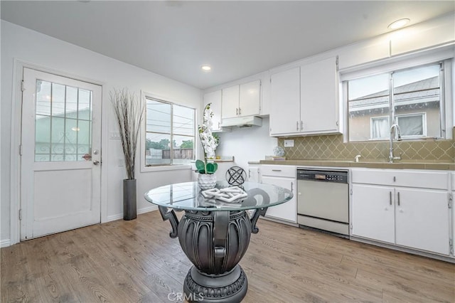 kitchen with white dishwasher, white cabinetry, light hardwood / wood-style floors, and sink