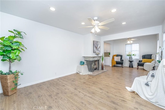 living room featuring a multi sided fireplace, ceiling fan, and light hardwood / wood-style floors