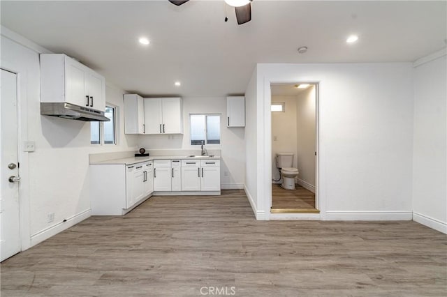 kitchen featuring ceiling fan, white cabinetry, sink, and light hardwood / wood-style flooring