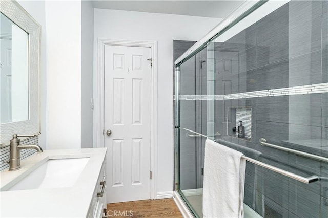 bathroom with hardwood / wood-style floors, vanity, and a shower with door