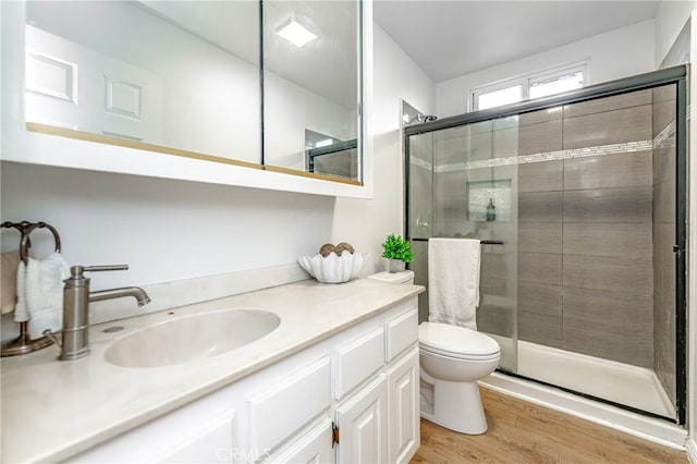 bathroom featuring wood-type flooring, vanity, toilet, and a shower with door