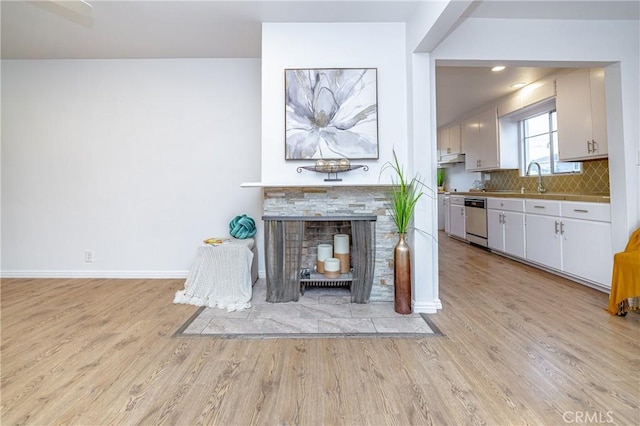 unfurnished living room with a fireplace, light wood-type flooring, and sink