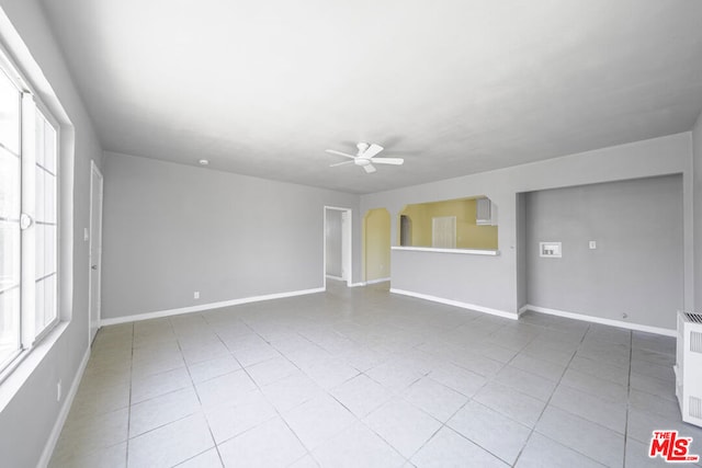 unfurnished room featuring a wealth of natural light, radiator heating unit, and ceiling fan