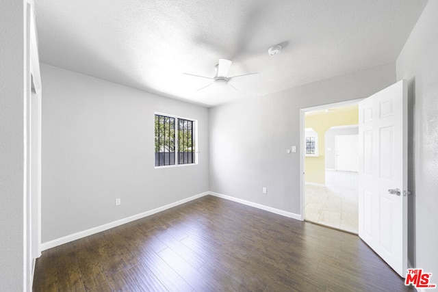 empty room with ceiling fan, dark hardwood / wood-style flooring, and a textured ceiling