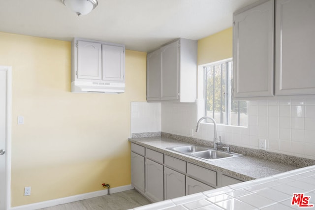 kitchen with decorative backsplash, gray cabinets, and sink