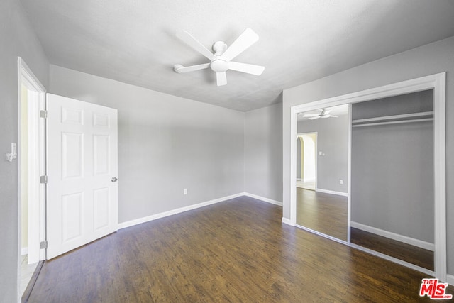 unfurnished bedroom featuring ceiling fan, dark hardwood / wood-style flooring, and a closet