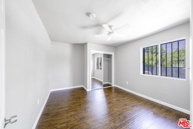 unfurnished bedroom featuring ceiling fan, dark hardwood / wood-style flooring, and a closet