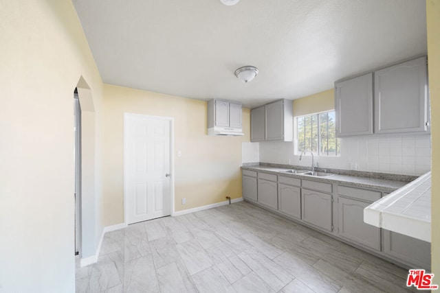 kitchen featuring tile countertops, gray cabinets, and sink