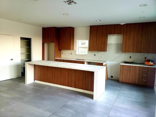 kitchen with concrete flooring, decorative backsplash, and a center island