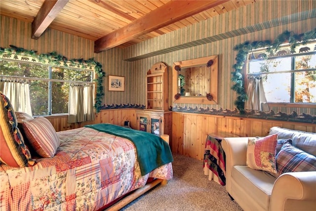 carpeted bedroom with multiple windows, wooden walls, beamed ceiling, and wooden ceiling