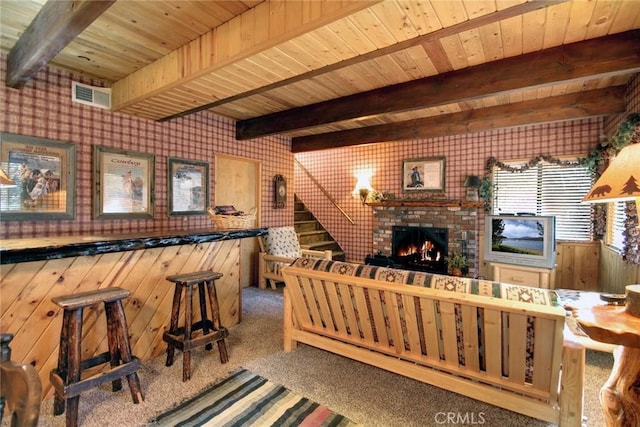 living room featuring wood walls, beamed ceiling, wood ceiling, and a brick fireplace