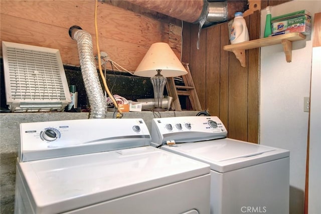 laundry room with wooden walls and washing machine and clothes dryer