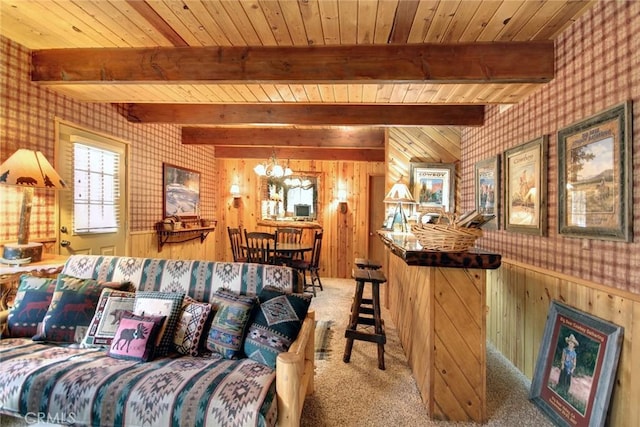 living room featuring beamed ceiling, a notable chandelier, carpet flooring, and wooden walls