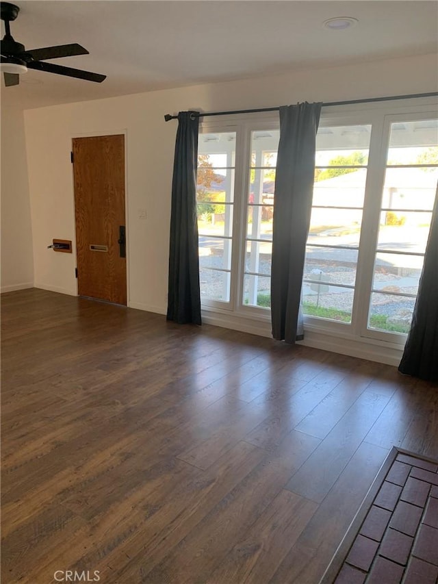 spare room with dark hardwood / wood-style floors, ceiling fan, and a healthy amount of sunlight