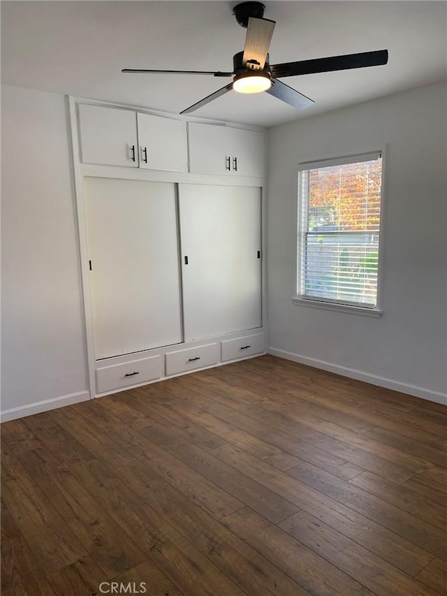 unfurnished bedroom featuring a closet, ceiling fan, and dark hardwood / wood-style flooring