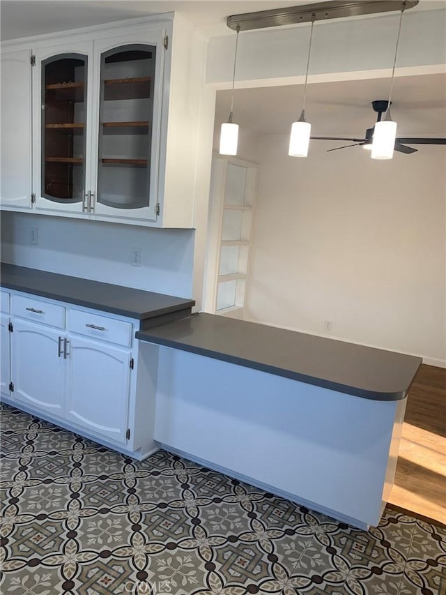 kitchen featuring white cabinetry, ceiling fan, kitchen peninsula, decorative light fixtures, and dark tile patterned flooring