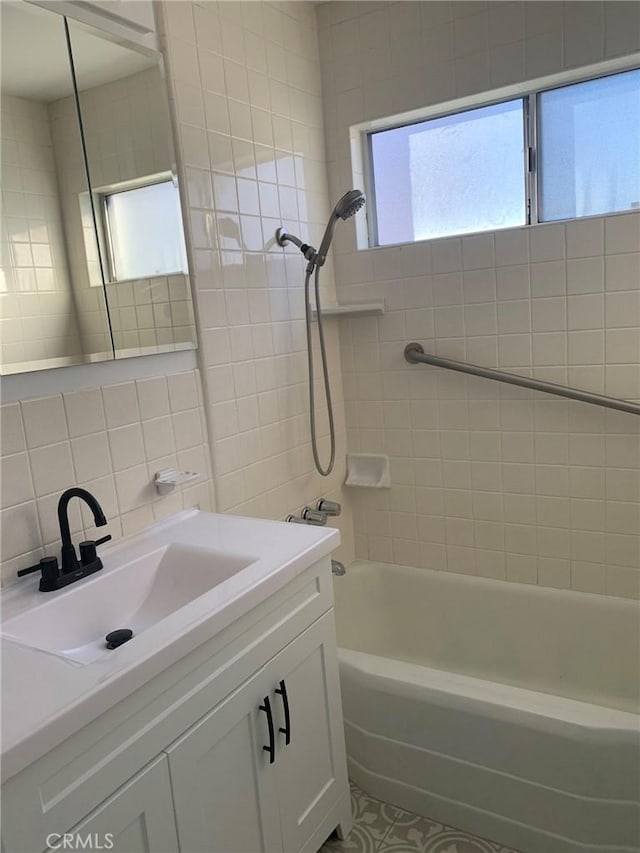 bathroom featuring decorative backsplash, vanity, tiled shower / bath, and tile walls