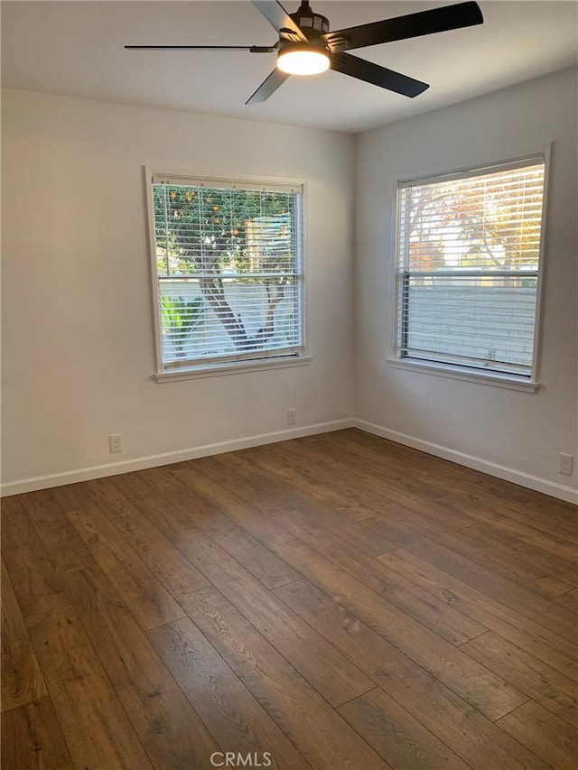 spare room with a wealth of natural light, ceiling fan, and dark hardwood / wood-style floors