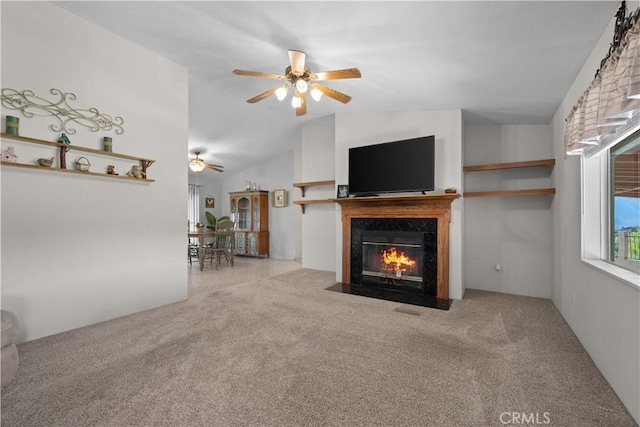 unfurnished living room with a high end fireplace, ceiling fan, light carpet, and vaulted ceiling