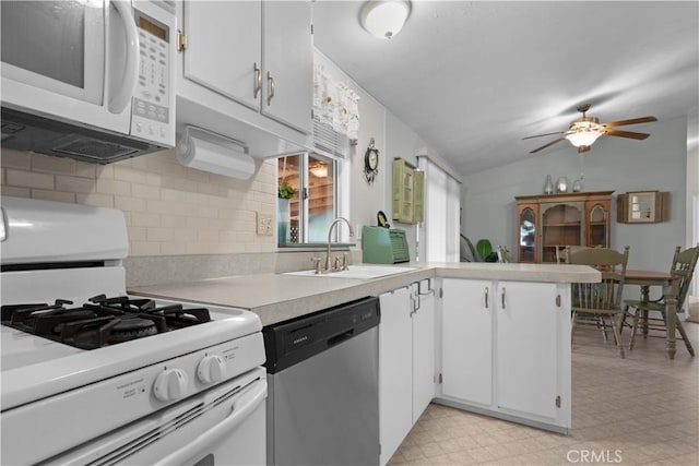 kitchen featuring white appliances, kitchen peninsula, sink, white cabinetry, and lofted ceiling