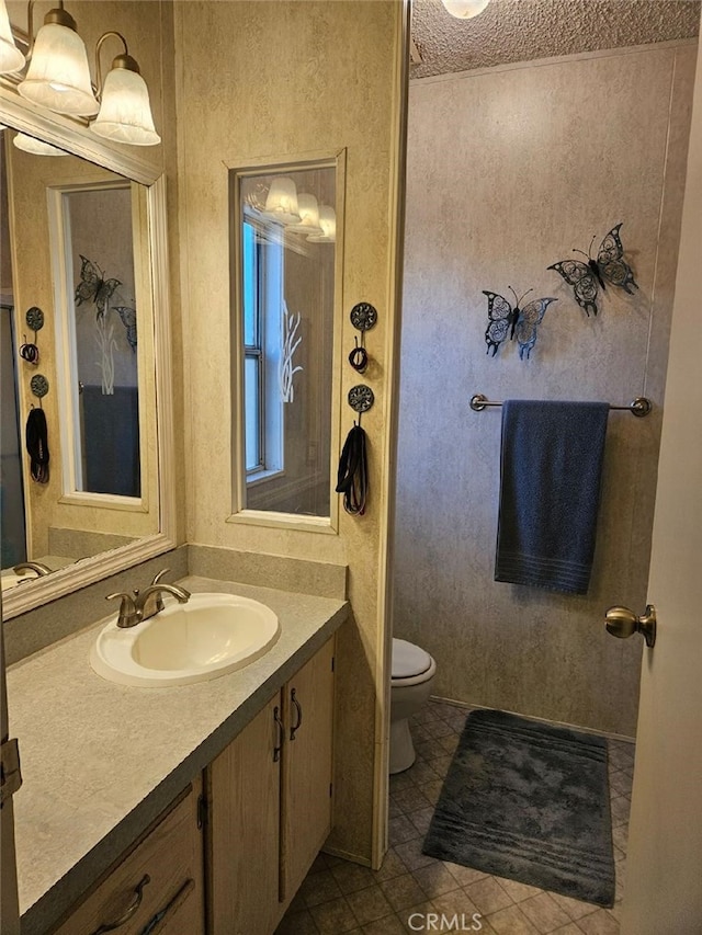 bathroom featuring toilet, tile patterned flooring, vanity, and a textured ceiling