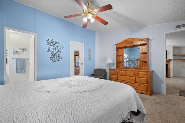 carpeted bedroom featuring ensuite bathroom, a textured ceiling, and ceiling fan