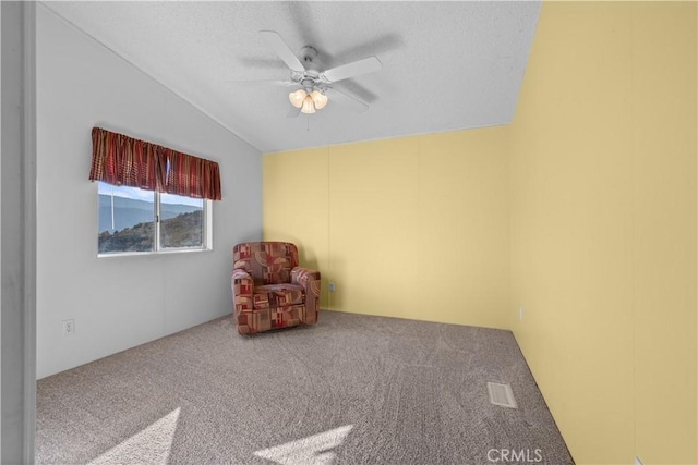 unfurnished room with ceiling fan, vaulted ceiling, a textured ceiling, and carpet flooring