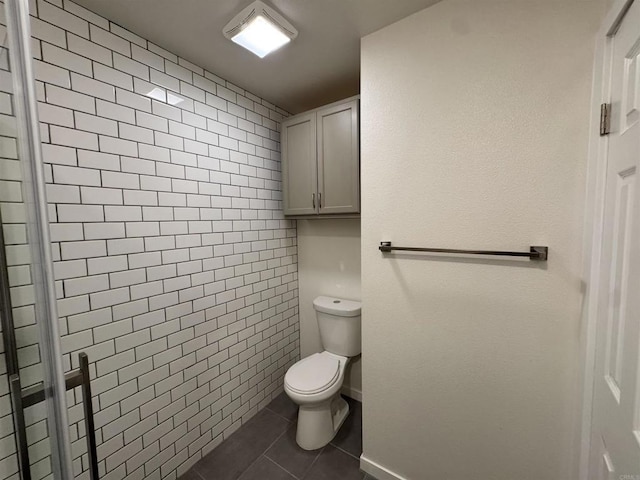 bathroom with tile patterned flooring, toilet, walk in shower, and tile walls