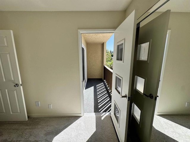 hall with dark colored carpet