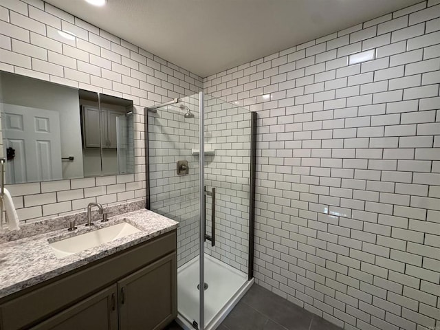 bathroom featuring vanity, a shower with door, tile patterned floors, decorative backsplash, and tile walls