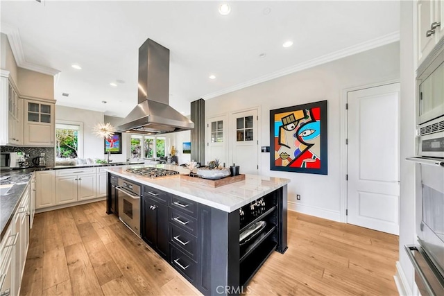 kitchen featuring a center island, light hardwood / wood-style floors, island exhaust hood, and appliances with stainless steel finishes