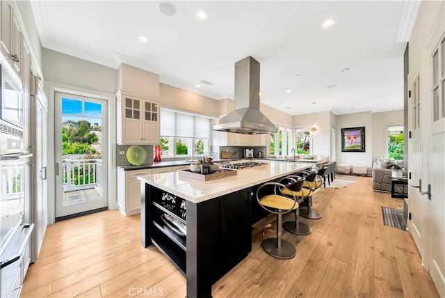 kitchen featuring a large island, island exhaust hood, a wealth of natural light, and light hardwood / wood-style flooring