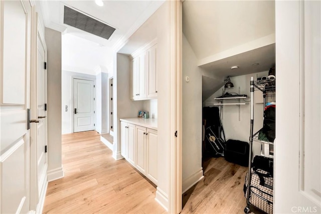 hallway with light hardwood / wood-style floors and ornamental molding