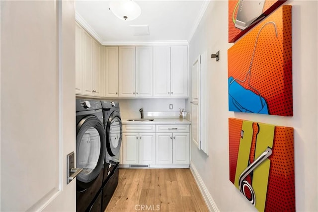 laundry room with cabinets, crown molding, sink, independent washer and dryer, and light hardwood / wood-style floors