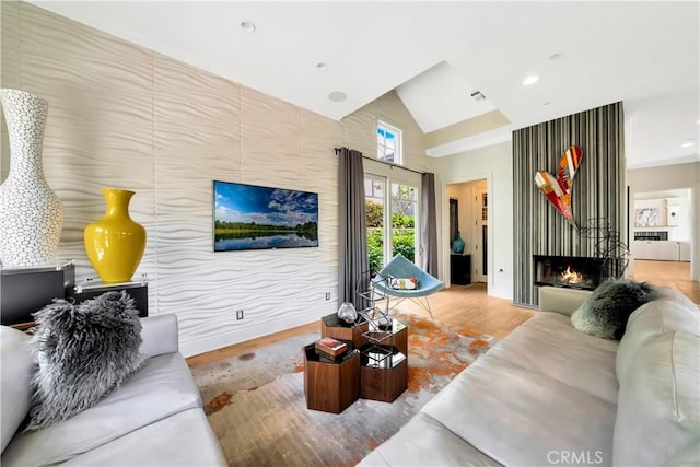 living room with a tiled fireplace, hardwood / wood-style floors, and lofted ceiling