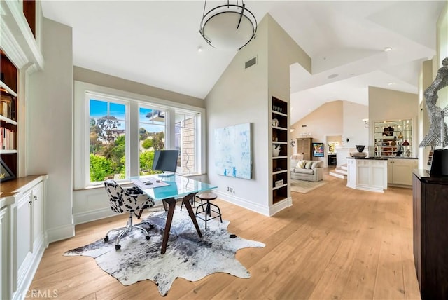 office with high vaulted ceiling and light hardwood / wood-style flooring