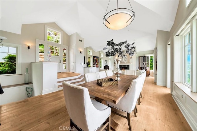 dining area featuring light hardwood / wood-style flooring and high vaulted ceiling