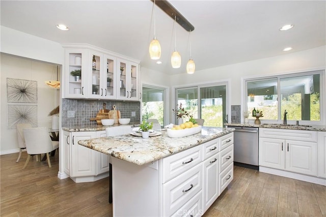 kitchen featuring white cabinetry, dishwasher, sink, wood-type flooring, and a kitchen island