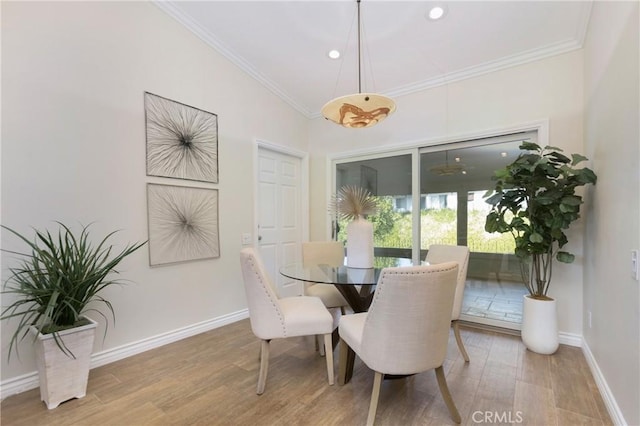 dining room with wood-type flooring, vaulted ceiling, and ornamental molding