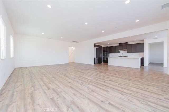 unfurnished living room with light wood-type flooring and sink