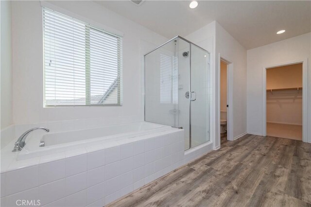 bathroom with toilet, plenty of natural light, independent shower and bath, and hardwood / wood-style flooring