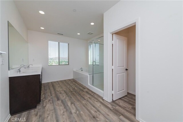 bathroom featuring hardwood / wood-style flooring, vanity, and plus walk in shower