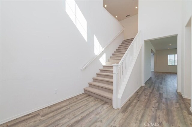 staircase featuring hardwood / wood-style flooring and a towering ceiling