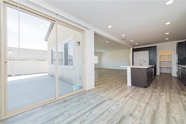 kitchen with a kitchen island with sink, sink, and light wood-type flooring