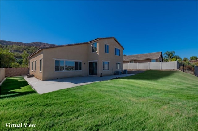 back of house featuring a yard, a patio area, a fenced backyard, and stucco siding