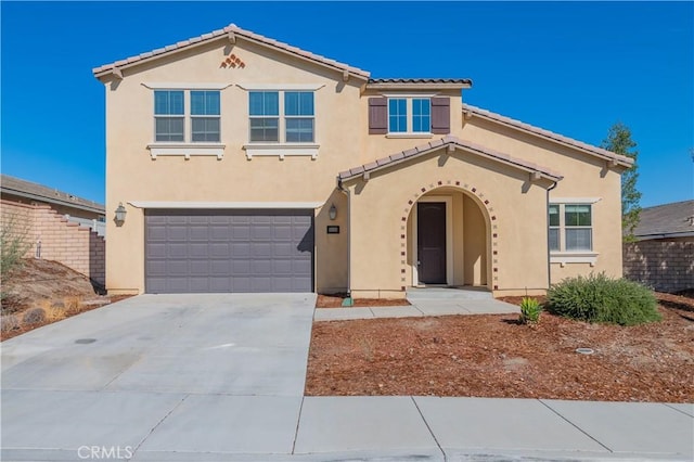 mediterranean / spanish home with a tile roof, driveway, an attached garage, and stucco siding