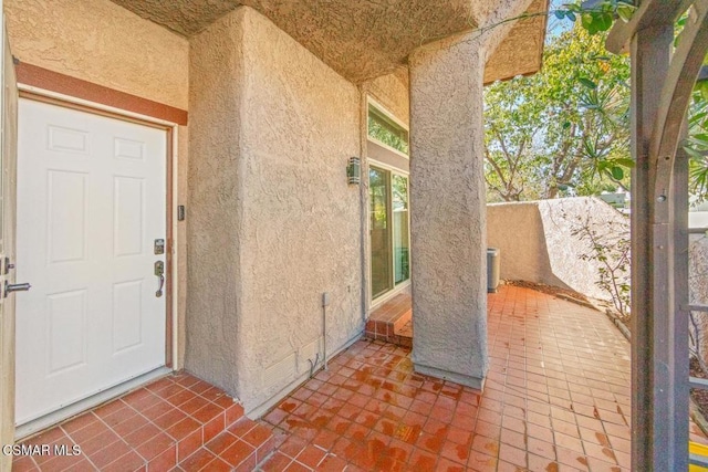 view of exterior entry with a patio and central AC