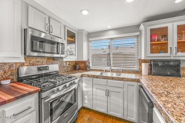 kitchen featuring sink, light hardwood / wood-style flooring, wooden counters, decorative backsplash, and appliances with stainless steel finishes